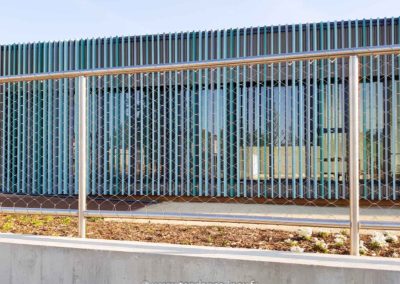 Garde-corps en maille inox 60x104 mm installé devant un bâtiment moderne, offrant sécurité et transparence.