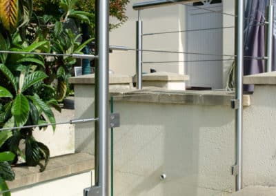 Détail du garde-corps inox avec soubassement en verre s'adaptant à un muret en escalier